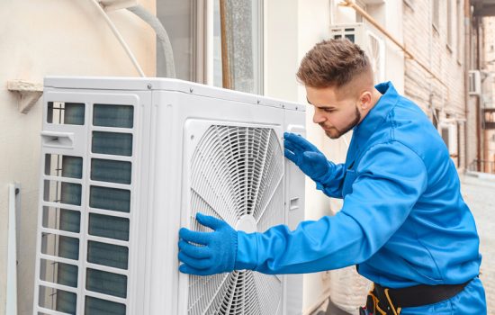 Male technician installing outdoor unit of air conditioner